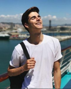 Joel - personagem ficticio, jovem de 26 anos com camiseta branca olhando para o céu de olhos fechados segurando uma mochila